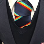 Close up of founders tie with three striped colours : red, yellow and cyan.