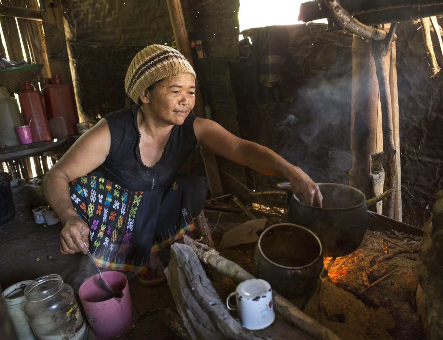 An old Asian lady is cooking with wood fire in her hut, Flores island in Indonesia.