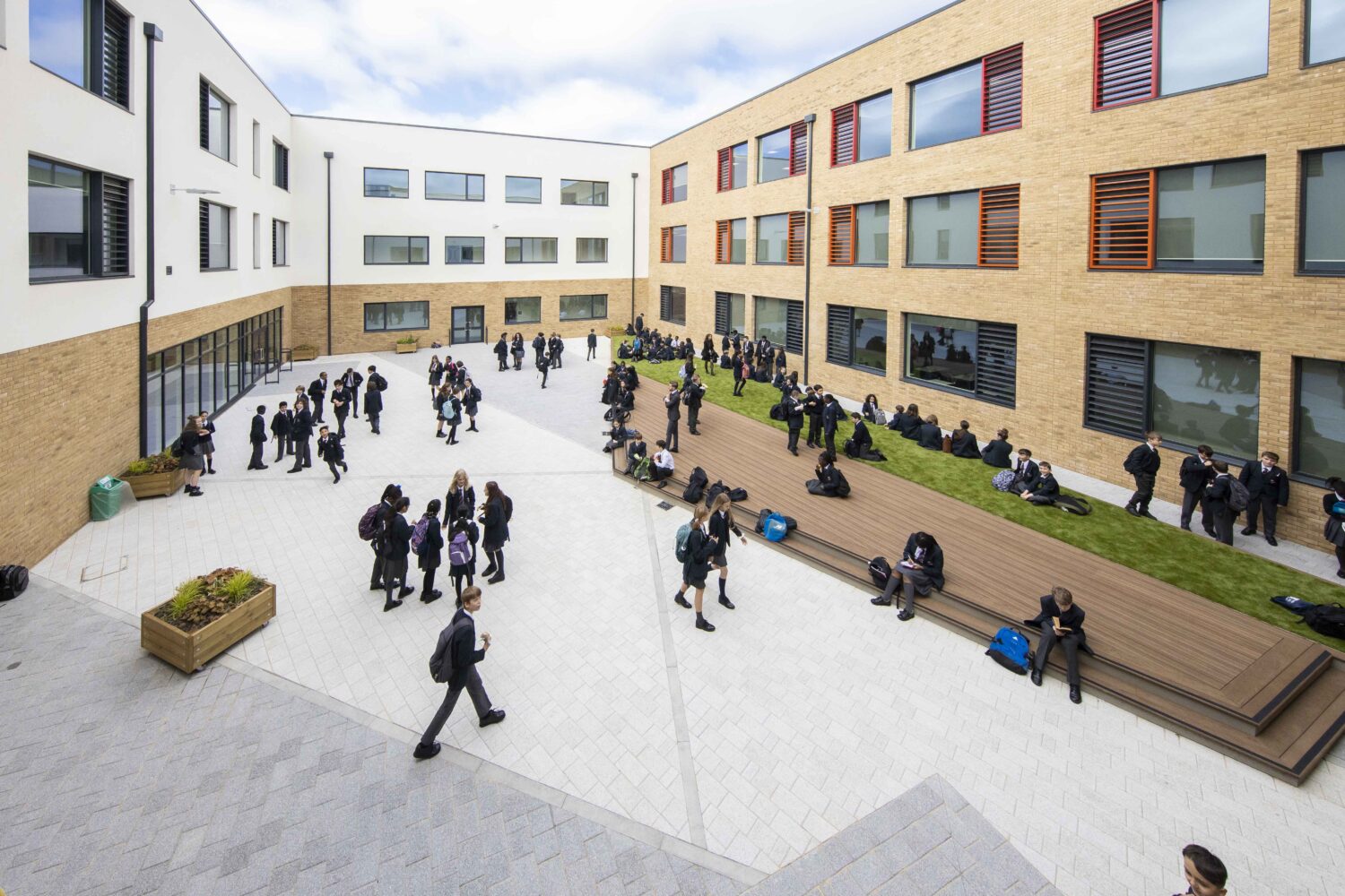 Wide-pan view of outside area with some students walking through, some sitting, some chatting in groups