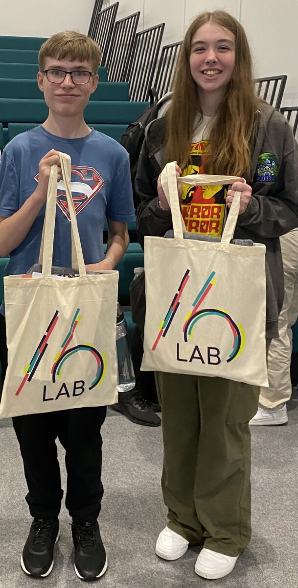 Two students holding branded LAB16 tote bags