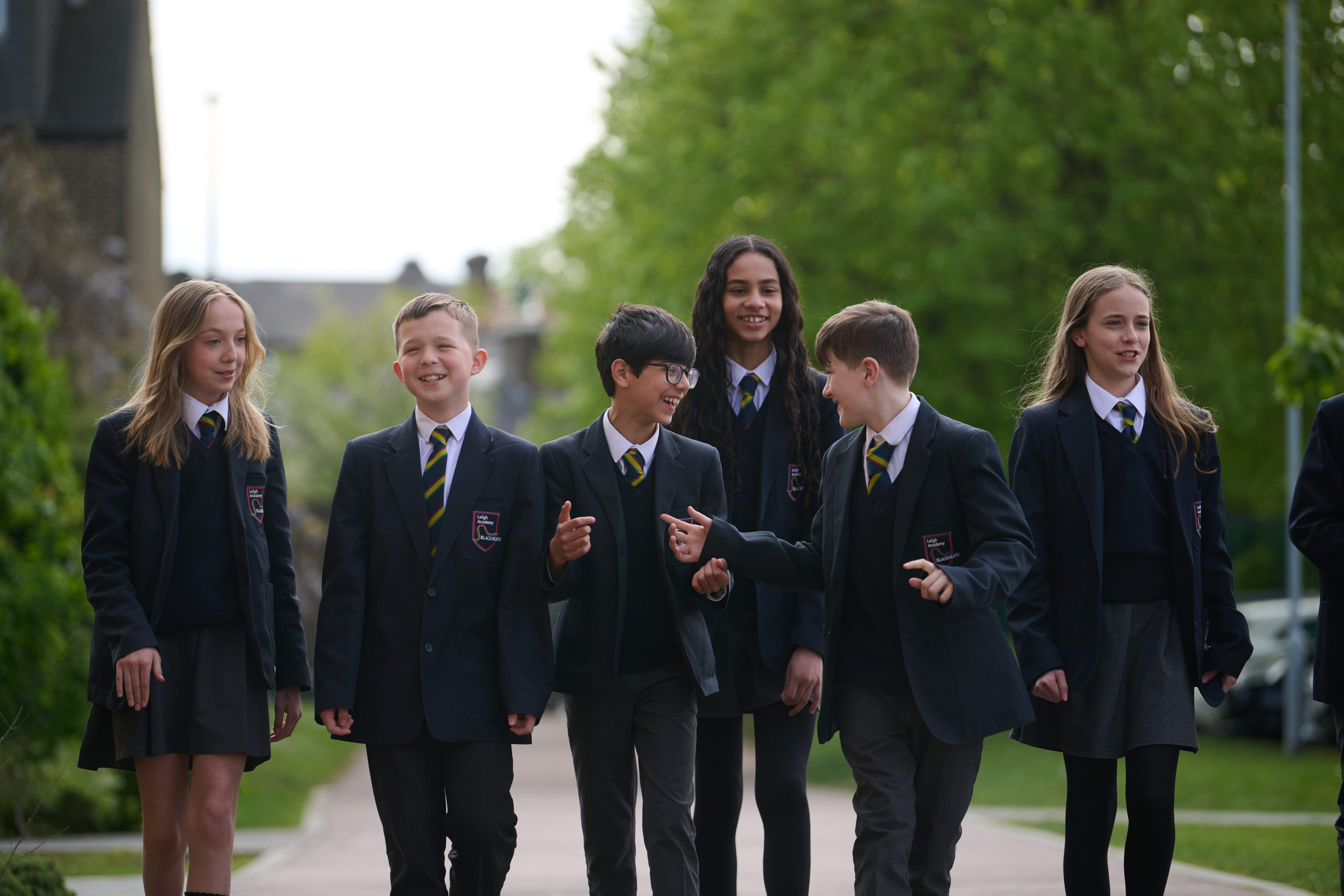 A group of students walking towards the camera, laughing and talking