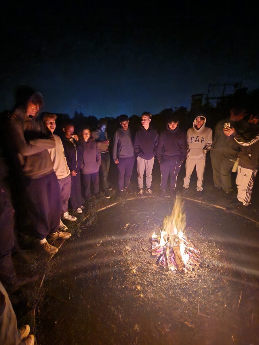 A group of students stood around a fire