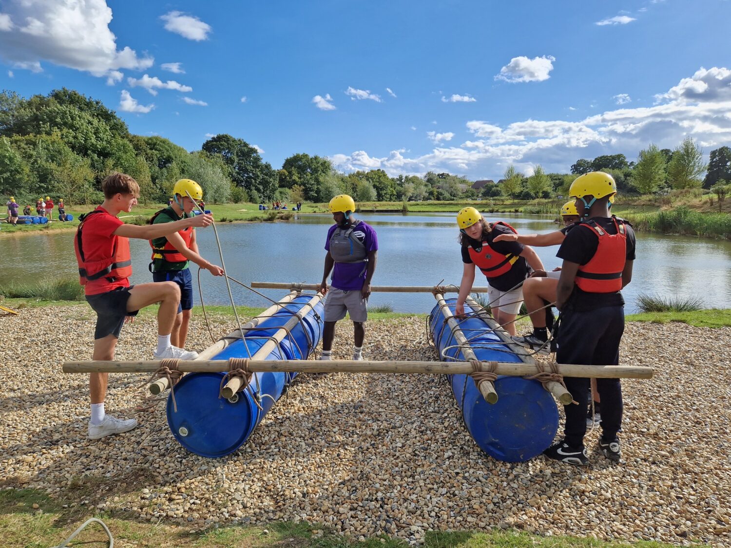 Several students around a raft made from barrels