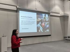 Someone in front of a presentation on a screen speaking